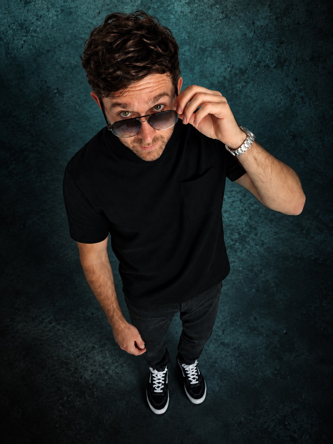Joe Drama lowering his sunglasses in a full-length studio portrait